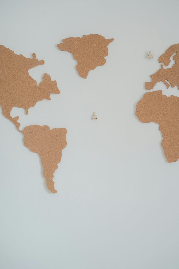 Cork world map pieces on a white wall, emphasizing minimalism and geography.