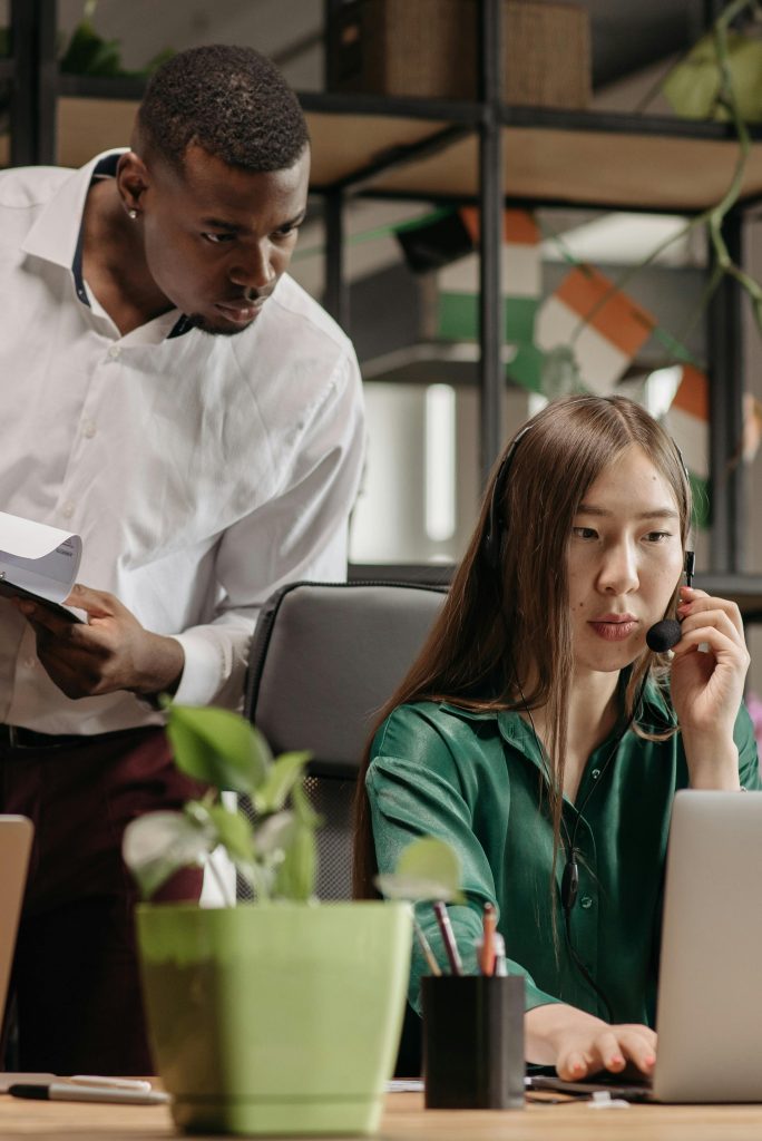 Two call center agents collaborating in a modern office environment, focusing on teamwork and productivity.