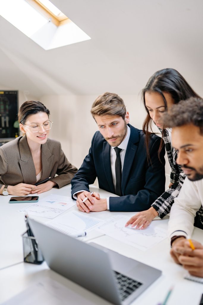 A diverse team of professionals engages in a collaborative office meeting, reviewing documents and strategies.