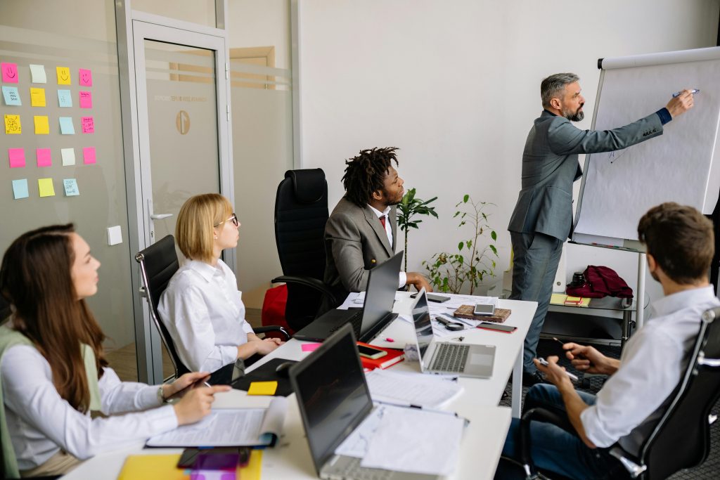Business team engaged in a collaborative meeting with a leader presenting on a flip chart.